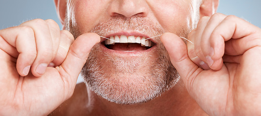 Image showing Closeup, floss and man with dental health, cleaning teeth and fresh breath against grey studio background. Male, gentleman and string for oral hygiene, wellness and morning routine for mouth grooming