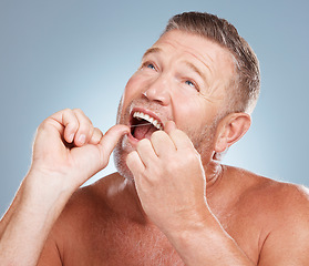 Image showing Dental, floss and face of man in studio isolated on a gray background for health. Oral hygiene, wellness and thinking senior male model with thread or string for flossing, cleaning or teeth care.