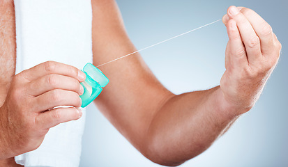 Image showing Hands, dental and floss product in studio isolated on a blue background for oral hygiene. Health, wellness and senior man model holding container with thread for flossing, cleaning and teeth care.