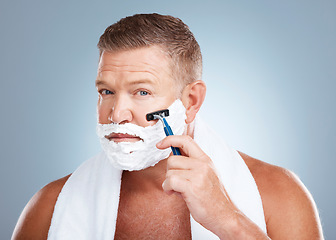 Image showing Face, shaving cream and man with razor in studio isolated on a blue background for hair removal. Portrait, skincare and mature male model with facial foam to shave for aesthetics, health or wellness