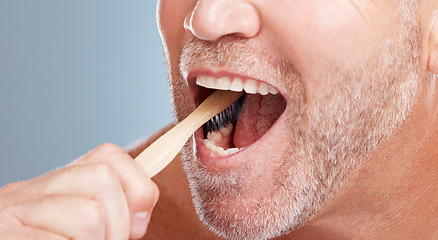 Image showing Cleaning, mouth or hand brushing teeth with dental toothpaste for healthy oral hygiene grooming in studio. Eco friendly, zoom or senior man with a natural bamboo wood toothbrush for teeth whitening