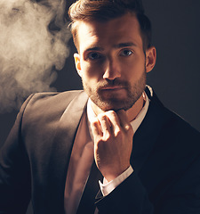 Image showing Portrait, smoke and man in suit, fashion and executive with confidence on dark studio background. Face, male leader and elegant gentleman with vintage clothes, stylish outfit and smoking on backdrop