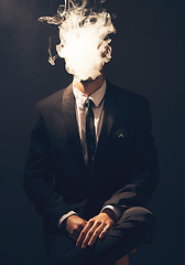 Image showing Businessman, suit and smoke in dark studio for corporate fashion, mafia aesthetic and success. Young model, man and smoking to hide face in secret for crime boss, vintage hand by black background