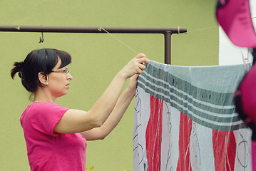 Image showing Woman hang laundry on clothesline strings
