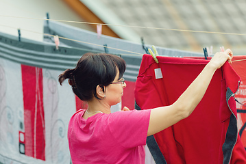 Image showing Woman hang laundry on clothesline strings