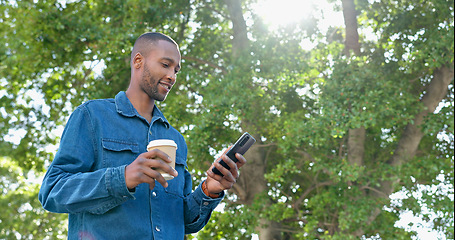 Image showing Park, texting and man relax with coffee, happy and calm in nature for travel, day off and tree background. Tea, black guy and online chat while standing in forest, casual and carefree on the weekend