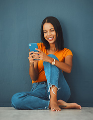 Image showing Happiness, black woman on floor and smartphone for connection, smile and communication on dark studio background. Female, lady and cellphone for typing, texting and social media for online reading