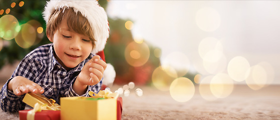 Image showing Boy, child or opening christmas present on living room floor, house or home with mockup, bokeh or mock up space. Smile, happy or festive kid with gift box in celebration, holiday or tradition giving