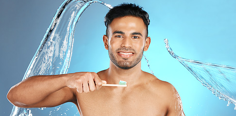 Image showing Dental, portrait and man brushing teeth in water splash, studio and mockup on blue background. Oral, hygiene and male teeth model with brush for mouth, cleaning and whitening product while isolated