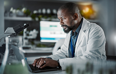 Image showing Scientist man, laptop and doing research in a laboratory with information technology and data analytics. Black person or doctor typing online at night for medical science development on internet