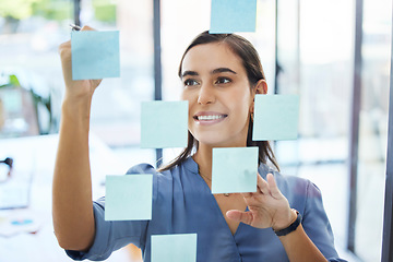 Image showing Business woman, brainstorming and planning schedule for goals, agenda and vision on office window. Happy young worker writing solution, sticky note ideas and strategy for company in startup agency