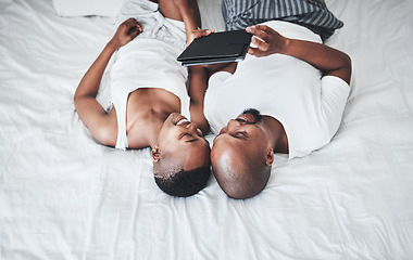 Image showing Black couple, tablet and relax on bed with smile for entertainment, browsing or social media at home. Happy African American man and woman relaxing in bedroom on touchscreen for morning streaming