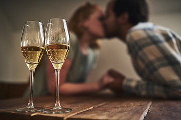 Image showing Champagne, glasses and love on valentines day with a couple kissing in the background of a restaurant for romance. Alcohol, drink or dating with a man and woman sharing a kiss on a romantic date