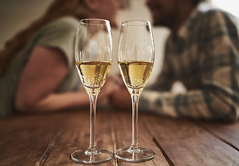 Image showing Champagne, glass and love on valentines day with a couple kissing in the background of a restaurant for romance. Alcohol, drink or dating with a man and woman sharing a kiss on a romantic date