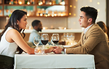 Image showing Couple holding hands, date in restaurant and celebrate Valentines day holiday with love, romance and fine dining. Commitment, interracial relationship and man with woman together, trust and support