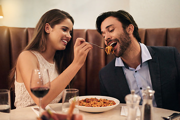 Image showing Romantic, date and woman feeding man spaghetti for dinner, supper and fine dining at a restaurant together. Couple, cute and happy lovers enjoying food, pasta and wine for valentines day