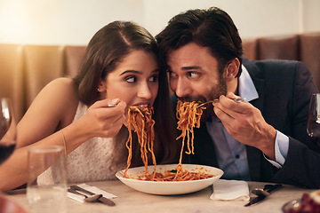 Image showing Hungry, restaurant and couple eating spaghetti for love, crazy fun and sharing plate on valentines date celebration. Happy people with pasta food for anniversary, dinner or fine dining experience