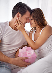 Image showing Man giving woman gift box, love and smile with partner, relationship and celebration on Valentines day. Couple with present, forehead touch and luxury, commitment and gratitude, celebrate holiday