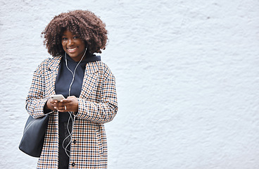 Image showing Black woman, phone and portrait smile listening to music with earphones in fashion and afro hairstyle on mockup. Happy African American female holding smartphone for audio track on a wall background