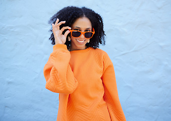 Image showing Trendy, portrait and woman with sunglasses by a wall in the city on a vacation or weekend trip. Happy, smile and female with orange, fashion or stylish eyewear in town while on a holiday in Mexico.