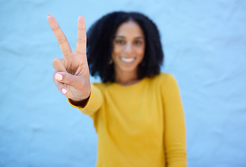 Image showing Black woman, hand and peace sign for victory, win or letter V against a blue wall background on mockup. Hand of happy African American female winner smiling showing peaceful symbol, gesture or emoji