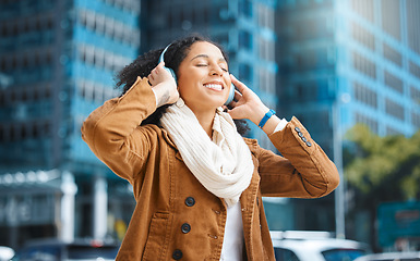 Image showing Black woman, headphones and listening to music in city for travel, motivation and happy mindset. Young person on an urban street with buildings background while streaming podcast or audio outdoor