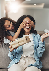 Image showing Mothers day, present and surprise of a child with a gift for mom in a living room. Wow, home and mother on a couch with a girl holding eyes closed with happiness and a smile in a house with box