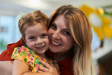 Image showing A cute little girl kissing and hugs her mother in preschool