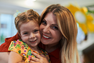 Image showing A cute little girl kissing and hugs her mother in preschool