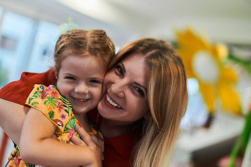 Image showing A cute little girl kissing and hugs her mother in preschool