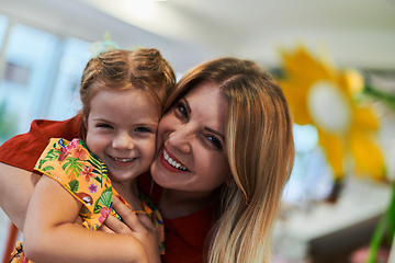 Image showing A cute little girl kissing and hugs her mother in preschool