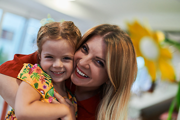 Image showing A cute little girl kissing and hugs her mother in preschool