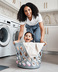 Image showing Happy mother with her child in a washing basket at their home while doing laundry together. Happiness. housework and portrait of a young woman having fun with her girl kid while cleaning the house.