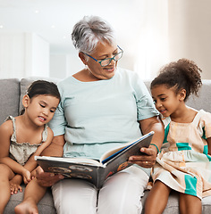 Image showing Family, grandmother and children with book reading on sofa for bonding, relaxing and quality time together. Love, education and elderly woman with girls learn to read story, fairy tale and literature