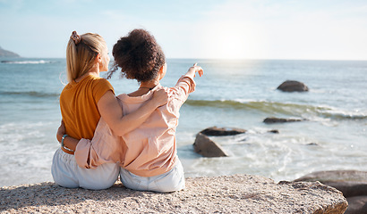 Image showing Beach, rear view and women pointing at the sea for travel, sightseeing or fun on vacation against blue sky background. Back, friends and ladies relax at ocean with peace, freedom and bond in Miami