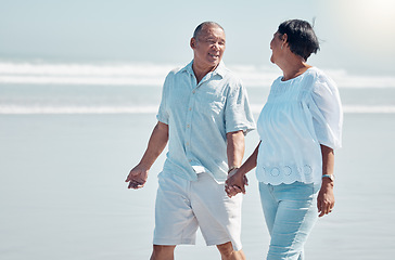 Image showing Retirement, love and walking on the beach with a senior couple outdoor together on the sand by the ocean. Nature, walk or holding hands with a mature man and woman outside with the sea or water