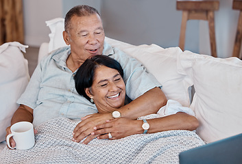 Image showing Senior couple watching a movie on a sofa with a laptop while relaxing in their living room. Love, coffee and happy elderly man and woman in retirement streaming a video on computer together on couch.