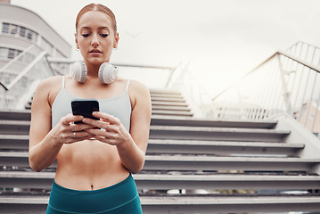 Image showing City, workout and woman with smartphone typing, communication, 5g and headphones after exercise. Health, training and personal trainer on phone texting, fitness app to connect or network in sports.