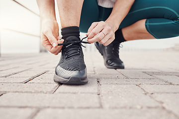 Image showing Shoes, runner and woman getting ready for training, exercise or running in sports sneakers, fashion and urban street. Feet of athlete or person tying her laces for cardio, fitness or workout outdoor