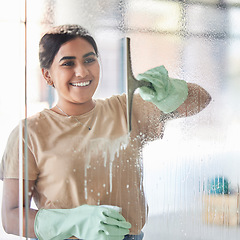 Image showing Happy, smile and girl cleaning window with spray bottle and soap or detergent, housekeeper in home or hotel. Housework, smudge and woman or professional cleaner service washing off glass in apartment