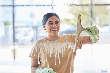 Image showing Smile, happy and housekeeper cleaning window with spray bottle and soap or detergent, housekeeping in home or hotel. Housework, smudge and woman or cleaner service washing dirt off glass in apartment