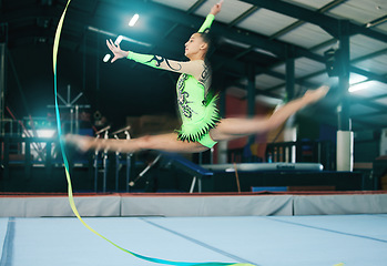 Image showing Gymnastics, woman and jump with ribbon and motion blur, sport in gym with action and speed for fitness. Athlete, moving with rhythmic gymnast, flexibility and pose with sports and splits in air