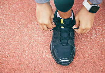 Image showing Hands, top view and woman tie shoes at running track, stadium or arena outdoors. Sports, training and black female athlete tying sneaker lace, getting ready and preparing for exercise, workout or run