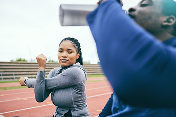 Image showing Running, sports and black woman stretching on race track for exercise, marathon training and fitness. Stadium, workout and athlete team warm up, drink water and ready for challenge, run and racing