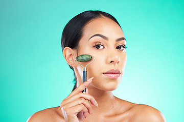 Image showing Portrait, jade roller and woman with face massage in studio for wellness, grooming or skincare on isolated blue background. Beauty, facial and massaging tool by girl model relax, skin or product