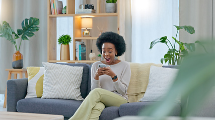 Image showing African woman celebrating a new job while sitting at home on a couch. A young females loan is approved via an email on her phone. A happy and excited lady cheering for a promotion on a sofa