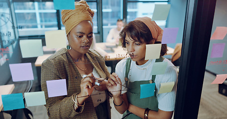 Image showing Sticky notes, planning and team writing on a board while analyzing research for a creative project. Collaboration, teamwork and female marketing employees working on advertising strategy in an office