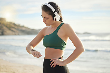 Image showing Headphones, smartwatch and beach woman for workout, exercise or runner results, progress or wellness. Goals, check timer and mental health of sports person listening to music, podcast by sea or ocean