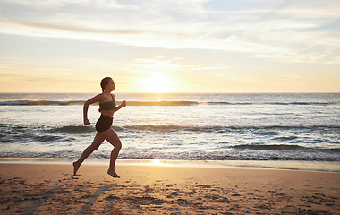 Image showing Woman, fitness and runner on the beach in sunset for healthy cardio exercise, training or workout in the outdoors. Female running or exercising in sunrise for health and wellness by the ocean coast