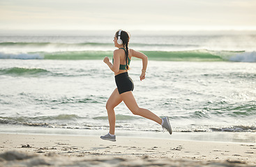 Image showing Woman running on beach, listening to music and morning cardio routine for healthy lifestyle in California. Fitness workout by sea, young athlete with headphones and sports exercise in summer